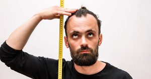 man measuring his height with a measuring tape