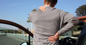 male car accident victim in pain squeezing neck and back